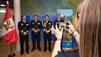 Woman taking a photo of four naval officers with her mobile phone