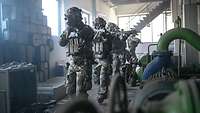 KSK-Soldaten laufen mit Waffen im Anschlag hintereinander in einem Gebäude