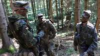 Drei Soldaten stehen im Wald und unterhalten sich.