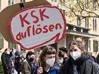 Eine Demonstrantin hält ein Pappschild mit der Aufschrift „KSK auflösen“