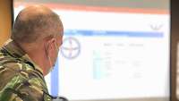 A soldier sitting at a table looks at a screen