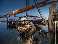 Zwei Soldaten mit Waffen im Anschlag kommen aus dem Wasser neben einem Bootssteg