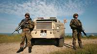 2 Soldiers in front of a military car