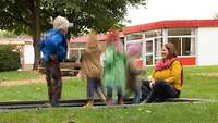 Ein Frau sitzt mit mehreren Kindern in einem Garten