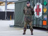 Ein Soldat steht vor einem Container mit einem roten Kreuz darauf