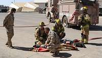 Ein Soldat kniet vor einem simulierten Verletzten, links steht ein jordanischer Soldat und weitere vier US-Feuerwehrmänner