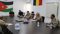 Drei Soldaten und zwei jordanische Mitarbeiter sitzen in einer Besprechung um einen Tisch herum