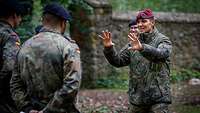 Mehrere Soldaten stehen im Halbkreis, vor ihnen steht ein Soldat, der mit starken Gesten spricht.