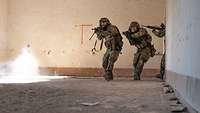 Mehrere Soldaten laufen schnell in einen großen Raum vor mit dem Gewehr im Anschlag