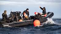 Mehrere Personen sitzen in einem Speedboot. Ein Taucher macht eine Rückwärtsrolle ins Wasser.