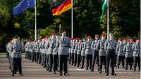 Zahlreiche Soldaten im grauen Dienstanzug sind angetreten, dahinter die Flaggen der EU, Deutschlands und Sachsens.