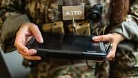Eine Soldatin hält ein tabletähnliches Gerät in den Händen