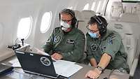 Zwei Soldaten an einem Laptop in einem Flugzeug