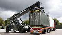 Ein Containerstapler hebt einen Container auf einen Lkw.