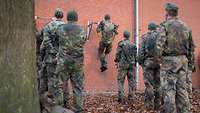 Soldaten machen Klimmzüge an einer Klimmzugstange, die an einer Mauer befestigt ist