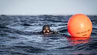 Ein Taucher schwimmt im Meer. Nben ihm schwimmt ein oranger Ball.