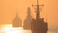 Drei Schiffe fahren bei Sonnenaufgang hintereinander 