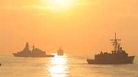 Drei Schiffe beim Sonnenaufgang auf dem Meer 
