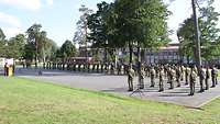Mehrere Soldaten stehen auf einem asphaltierten Platz der Kaserne in Formation.