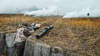 A soldier stands in his position with an antitank weapon next to him. The field in front of him has been fogged.