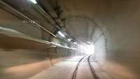 Straßenverlauf in einem Tunnel bis zu einer hellen Öffnung im Hintergrund.