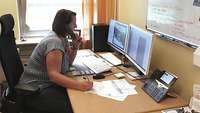 Woman sitting at a desk with two monitors on it