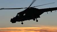 Hubschrauber fligt am Himmel im Sonnenuntergang