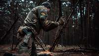 Ein Soldat kniet auf dem Waldboden und bereitet ein Baumhindernis vor 