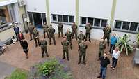 Soldaten und Zivilbeschäftigte stehen im Innenhof der Bundeswehrfachschule Koblenz.