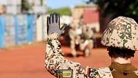 Eine Soldatin hebt den linken Arm und nimmt Verbindung mit einem Trupp Soldaten auf