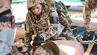 Eine Soldatin untersucht den Brustkorb eines verletzten Soldaten