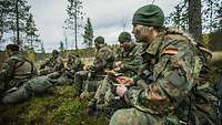 Soldaten sitzen mit Zettel und Stift im Gelände