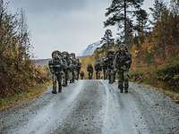 Soldaten marschieren mit Gepäck durch ein bergiges Gelände