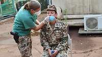 Eine Ärztin macht einen Nasenabstrich bei einer Soldatin