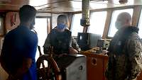 Der Embargo Control Liaison Officer, der Bordeinsatzoffizier und ein Besatzungsmitglied unterhalten sich. 