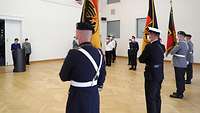 Soldaten stehen mit Flaggen vor Annegret Kramp-Karrenbauer im Stauffenberg-Saal