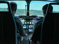 Zwei Männer sitzen im Cockpit eines Flugzeugsimulators.