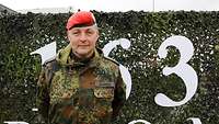 Ein Soldat steht vor einem Tarnnetz der Bundeswehr Portrait.