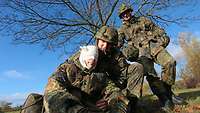 Soldat hilft seinem Kameraden mit verbundenen Kopf auf die Beine.