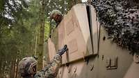 Zwei Soldaten arbeiten im Wald an einem Gefechtsfahrzeug. 