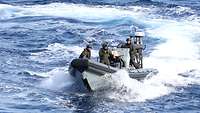 Drei Soldaten stehen in einem Boot und befinden sich in See