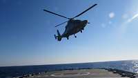 Ein Hubschrauber schwebt über dem Landeplatz an Bord eines Schiffes auf dem Meer 