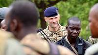 Ein deutscher Offizier betrachtet mehrere malische Soldaten