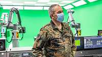 Ein Soldat steht in einem Filmstudio mit viel Technik und grell grünen Wänden.