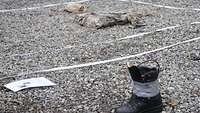 A Bundeswehr combat boot has been armed with a blasting cap and placed on a gravelled area.