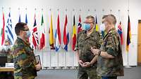 Two German soldiers and a Belgian soldier are talking.