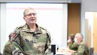 A French soldier speaks. In the background, soldiers sit at computers and work