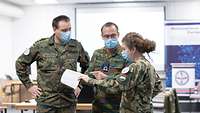 A Hungarian soldier, a Belgian soldier and a German soldier discuss a manuscript which the Belgian is holding