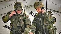 Zwei Soldaten drücken Schalter an Funkgeräten.