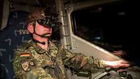 Ein Soldat mit Nachtsichtbrille sitzt am Steuer eines Fahrzeugs.